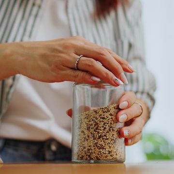 close up hand refilling glass jar containers with quinoa healthy eating,buying organic grains with reusable natural zero waste eco friendly sustainable food packaging eco friendly in sustainable plastic free grocery store