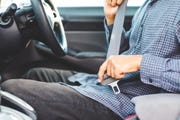 close up hands man sitting on car seat and fastening seat belt, car safety concept