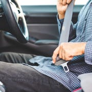 close up hands man sitting on car seat and fastening seat belt, car safety concept