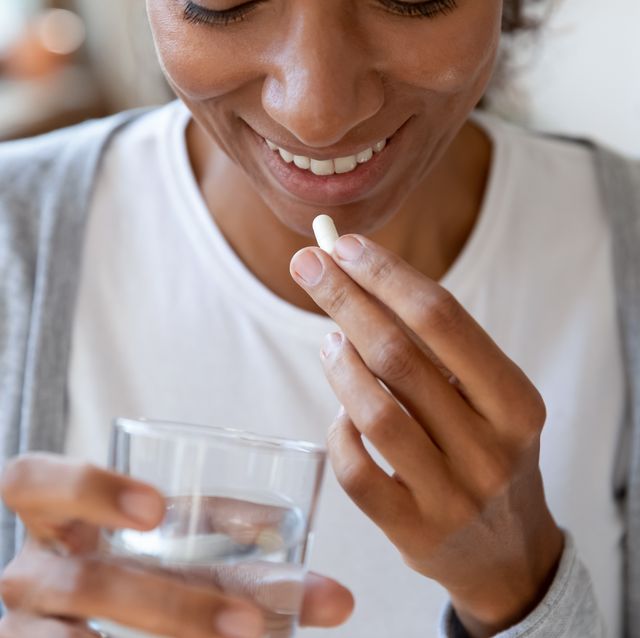 close up happy young african american young woman taking vitamins