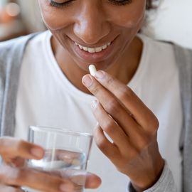 close up happy young african american young woman taking vitamins.
