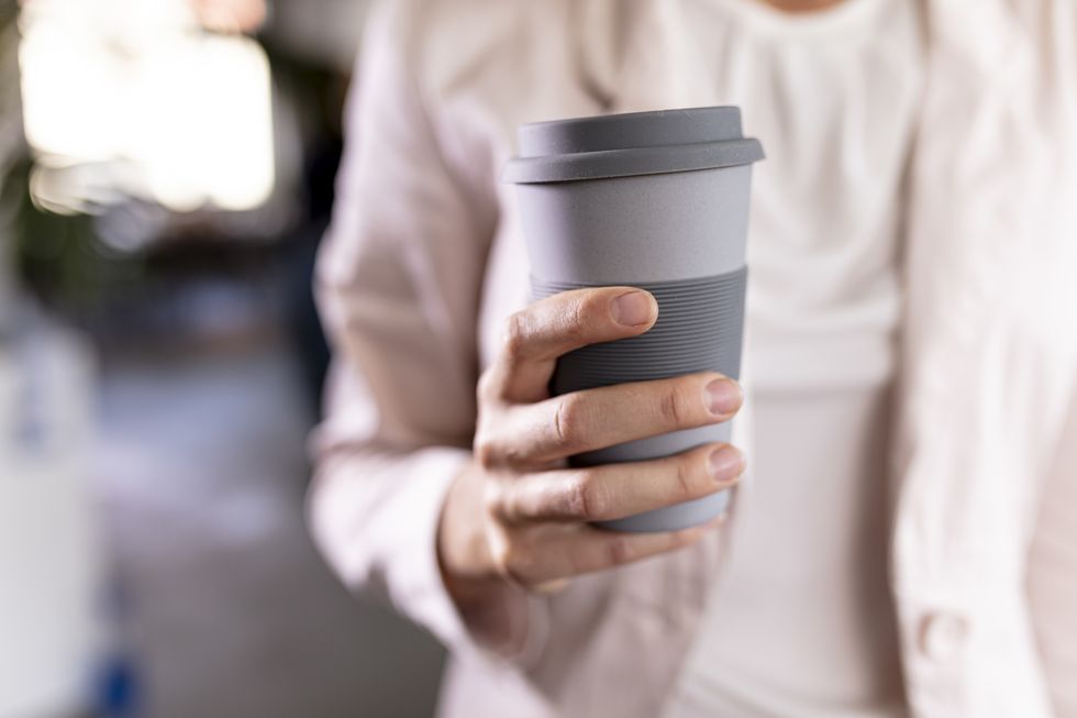 closeup of a businesswoman holding recycable takeaway coffee cup