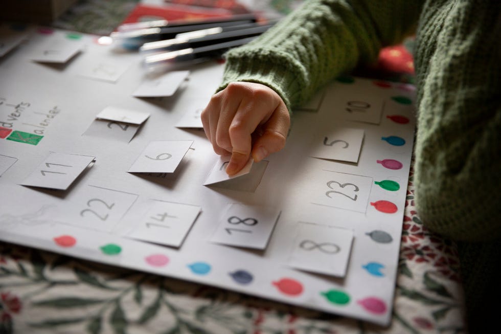 close up of a child opening the window of a simple, homemade, card advent calendar on a dining table
