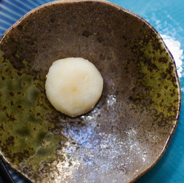 closeup of a chinese water chestnut on a brown plate which is resting on a blue plate