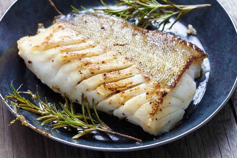 close up of a cod fillet with rosemary on a plate