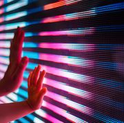 close up of a mother and kid's hand touching illuminated and multi coloured led display screen, connecting to the future