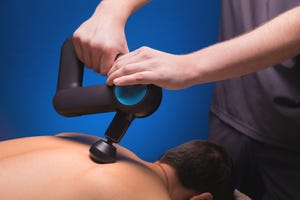 closeup of a professional male masseur stimulates the back muscles of a male patient in a dark spa