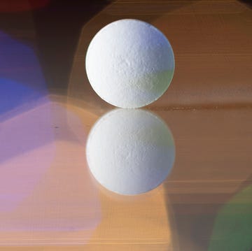 Close-up of a reflected pill on a reflective surface. Colorful lights background. close up of a reflected pill on a reflective surface colorful lights background