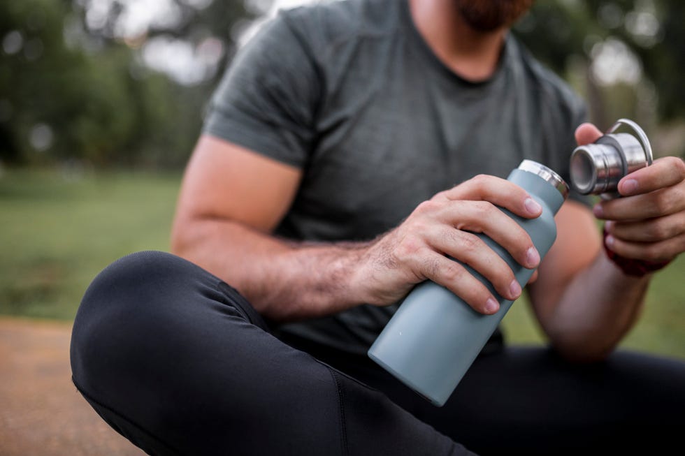 close up of a reusable water bottle in a human hand, concept of thirst, rehydration and decreasing single use plastic