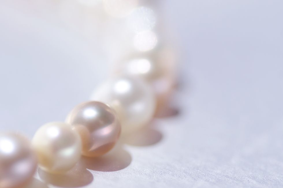 close up of a string of pink pearls on silver background with copy space