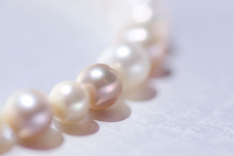 close up of a string of pink pearls on silver background with copy space