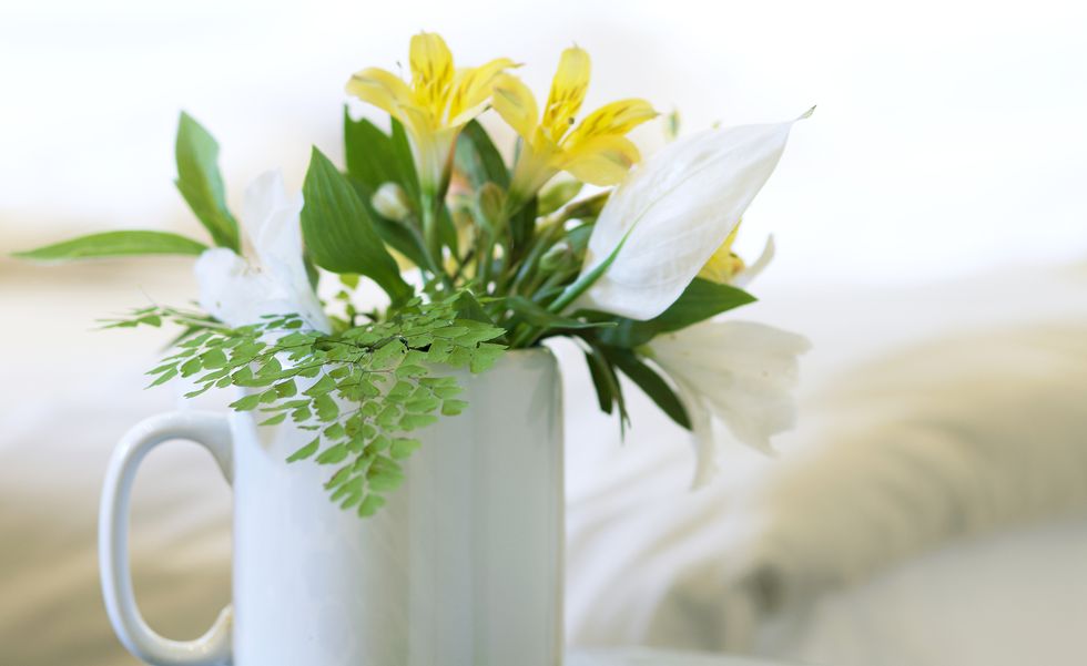 Close up of a white mug with a simple flower arrangement. Still life.