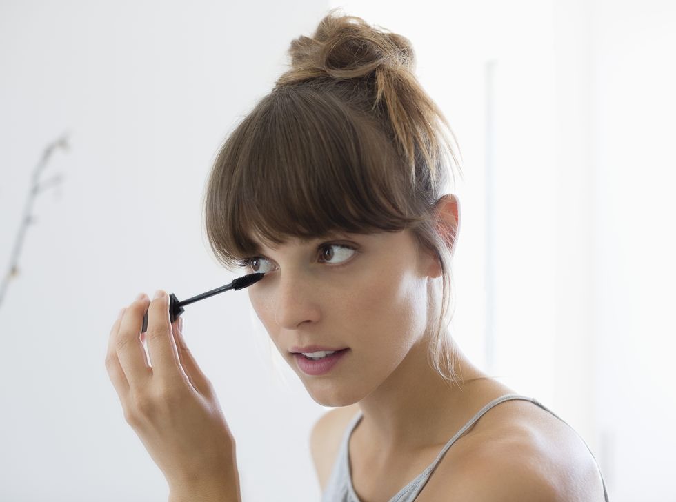 close up of a woman applying mascara