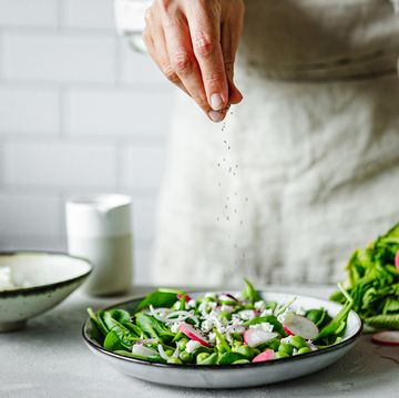 close up of a woman making healthy summer green salad in kitchen
