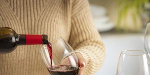 close up of a woman pouring red wine into a glass on party table