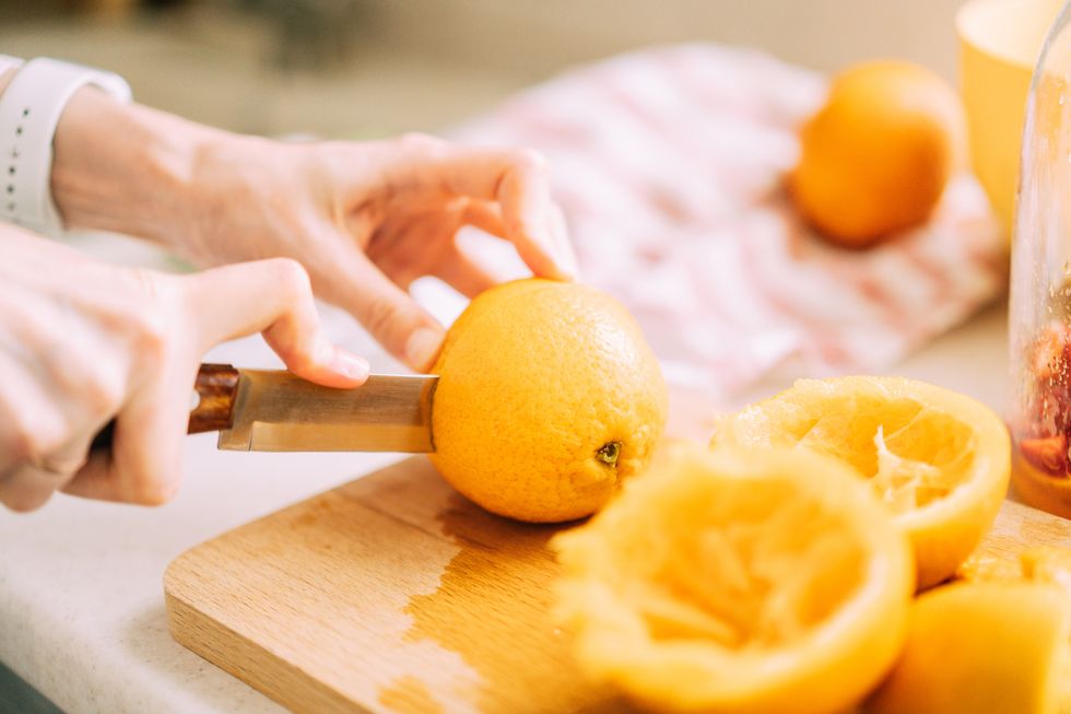 close up of a woman slicing oranges for cold refreshing drink