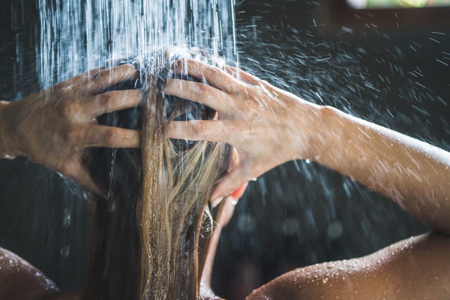 close up of a woman washing her hair while showering in the morning
