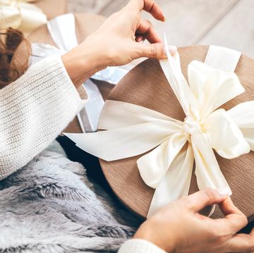 close up of a woman wrapping gifts and tying a beautiful pastel ribbon bow