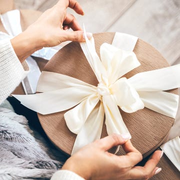 close up of a woman wrapping gifts and tying a beautiful pastel ribbon bow