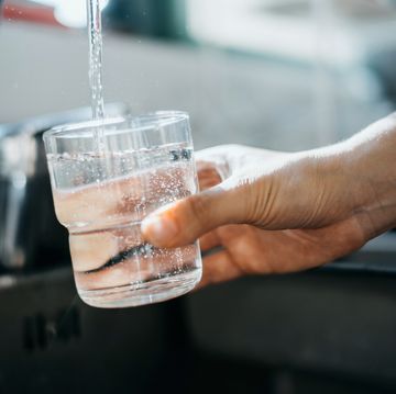 close up of a woman's hand filling a glass of filtered water right from the tap in the kitchen sink at home