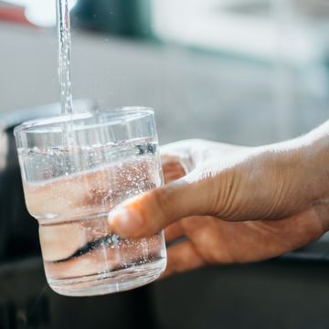 close up of a woman's hand filling a glass of filtered water right from the tap in the kitchen sink at home