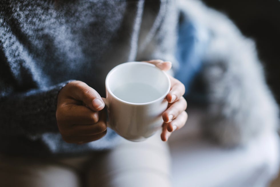 close up of a woman's hand holding a cup of hot water, vintage tone