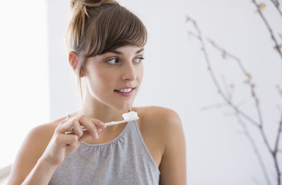 close up of a young beautiful woman brushing her teeth