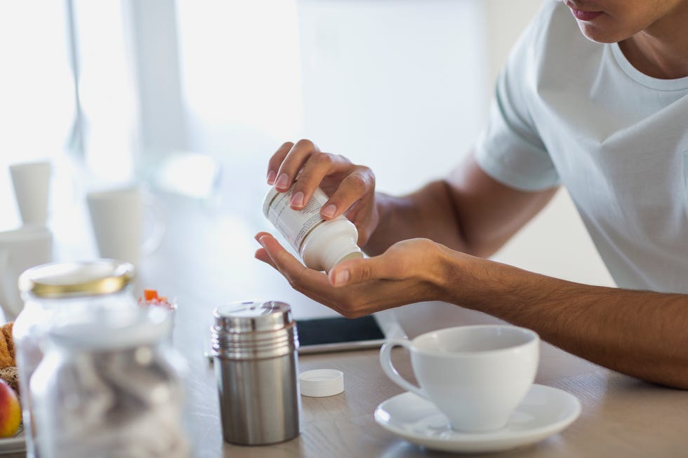 close up of a young man taking nutritional supplement pills