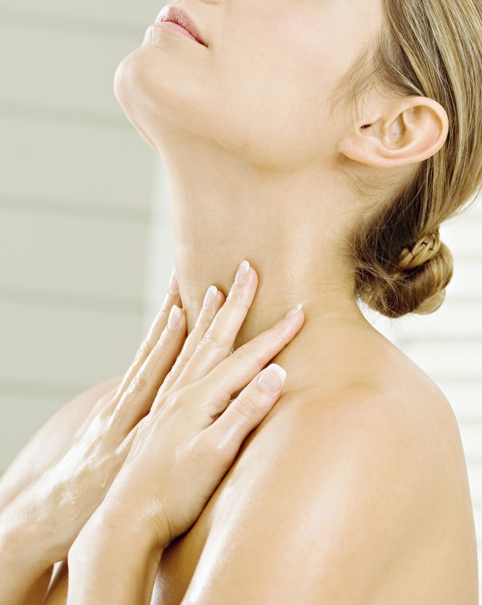 Close-up of a young woman applying moisturizer on her neck