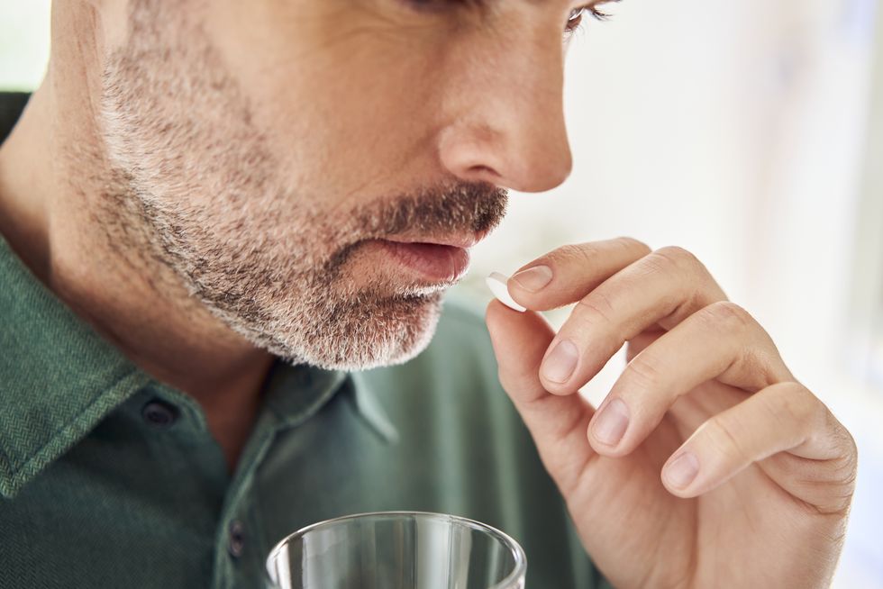 close up of adult man taking pill