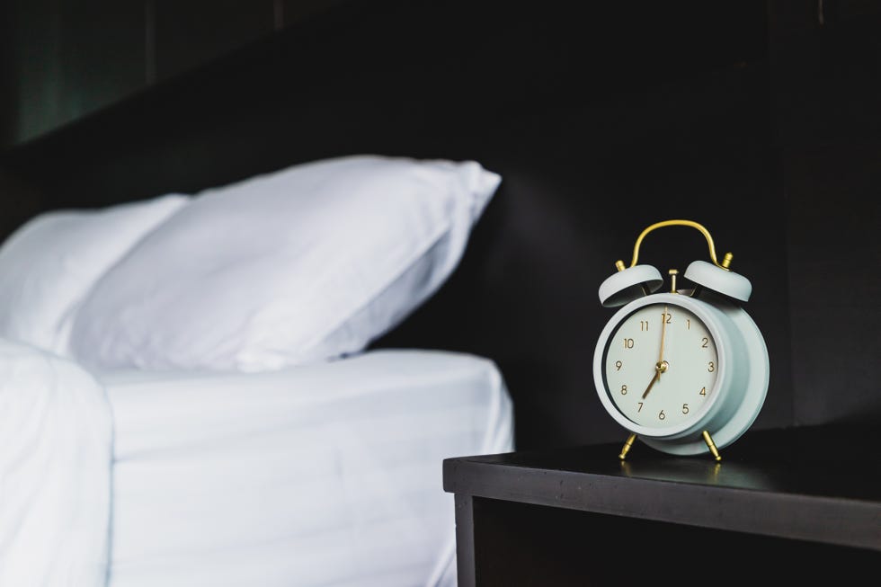 close up of alarm clock on night table against bed