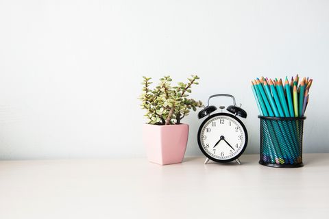 Close-Up Of Alarm Clock With Potted Plant And Pencils In Container On Table