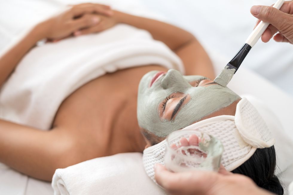 close up of applying facial mask on woman's face in a beauty spa