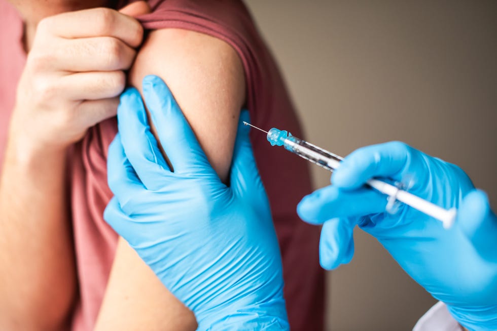 close up of arm of boy getting vaccinated by doctor holding a needle