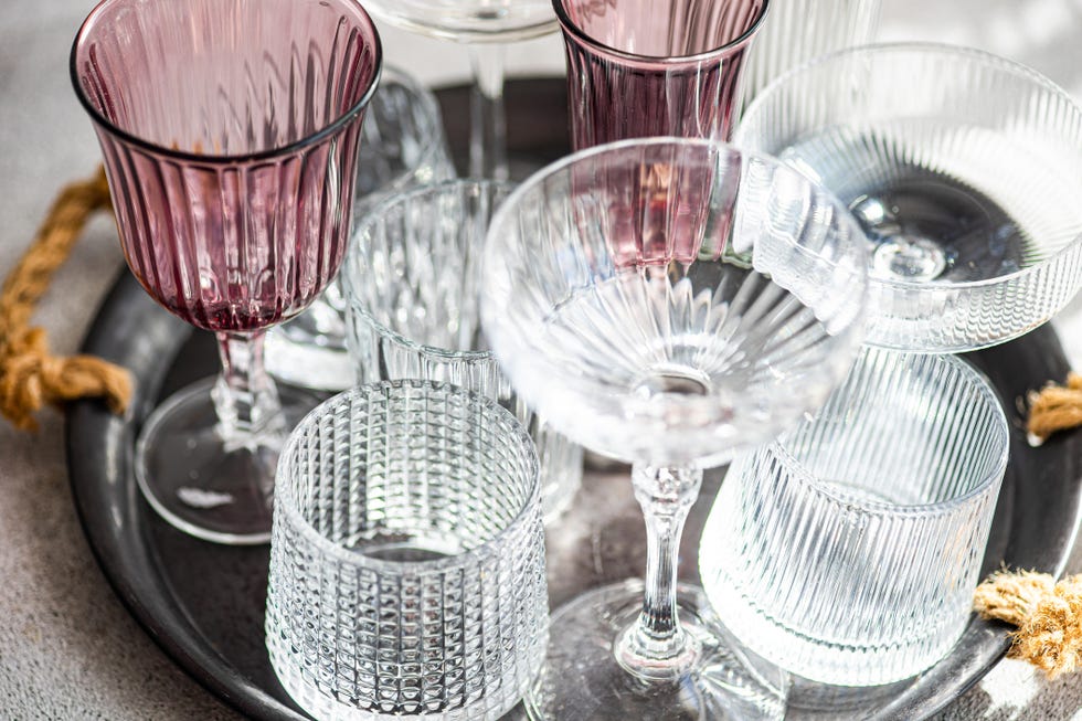 close up of assorted wine glasses, champagne coupes, tumblers and glasses on a tray in sunlight