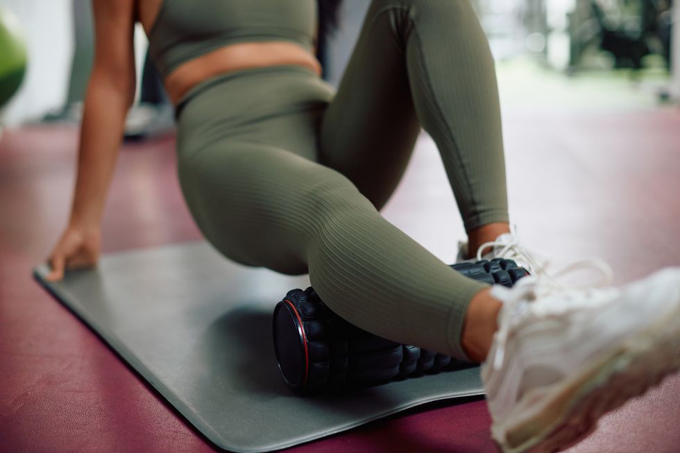 close up of athletic woman using foam roller while exercising in a gym