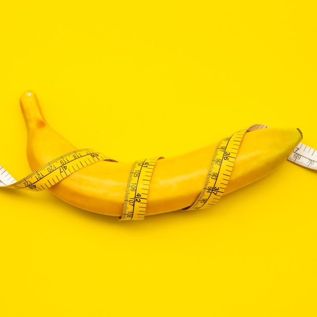 close up of banana wrapped with tape measure on yellow background
