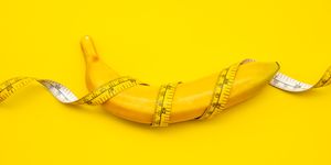 close up of banana wrapped with tape measure on yellow background