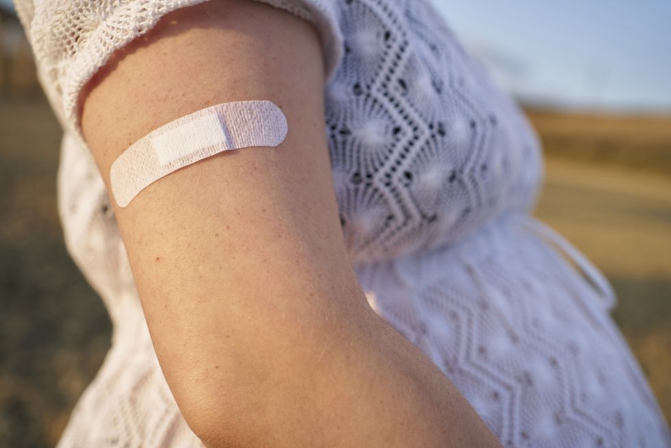 close up of band aid, on the arm young pregnant woman after giving her the vaccine