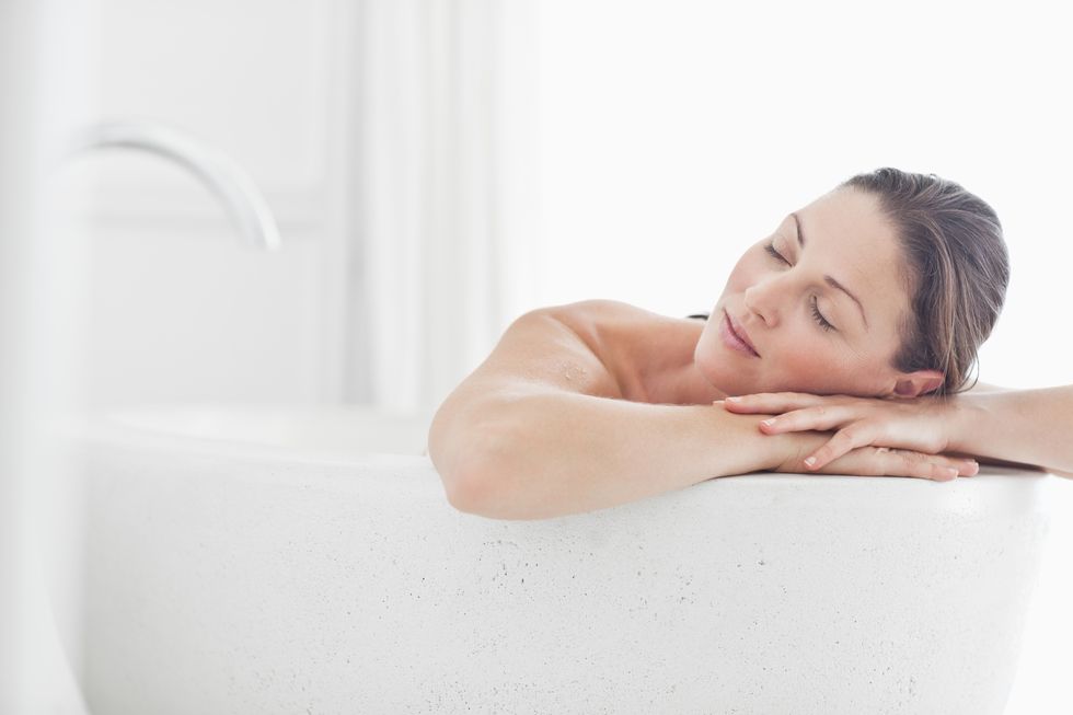 close up of beautiful mid adult woman relaxing in bathtub with eyes closed