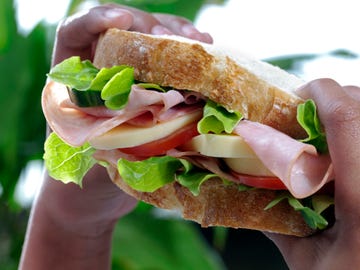 close up of big ham sandwich being held in small black hands