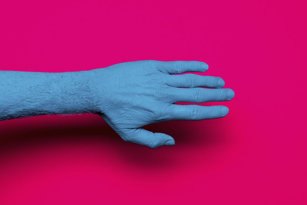 Close-up of blue painted hand over pink background