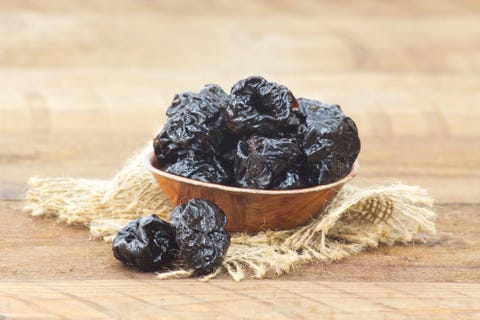 close up of bowl full of dried plums on table