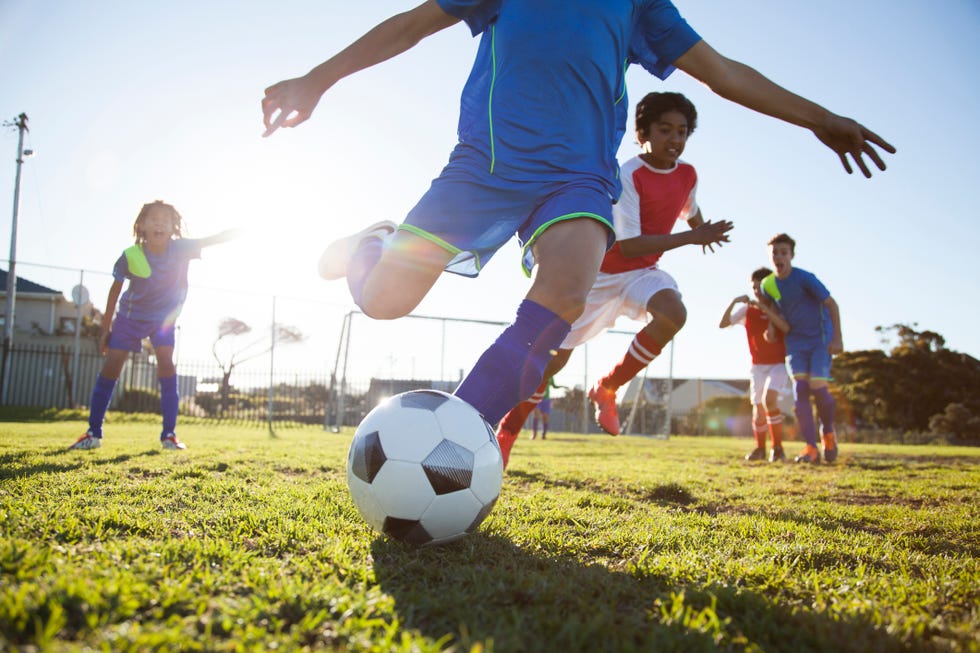 close up of boy kicking soccer ball