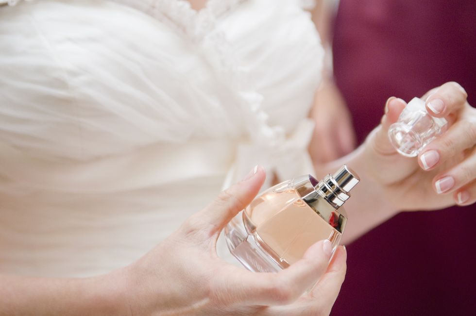 Close up of bride taking top off perfume bottle. 