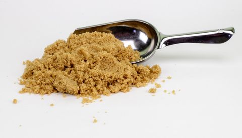close up of brown sugar and spoon on white background