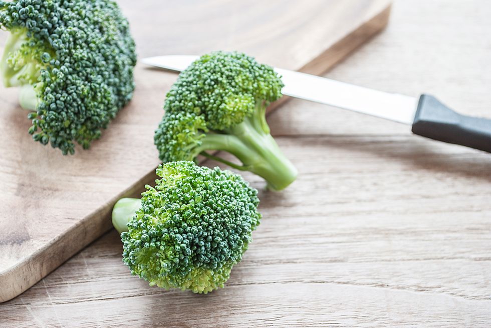 Close-Up Of Chopped Broccoli With Knife And Cutting Board On Table