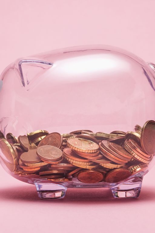 Close-Up Of Coin In Piggy Bank Against Pink Background