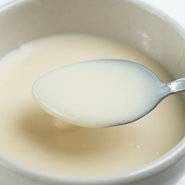 close up of condensed milk with spoon isolated on white background, food ingredients concept