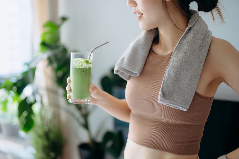 close up of confidence young asian sports woman taking a break, refreshing with healthy green juice after fitness work out  exercising  practicing yoga at home in the fresh bright morning